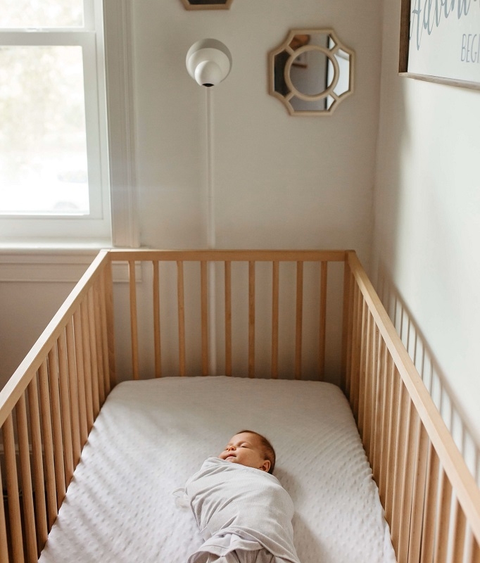 baby sleeping in a crib with Aura baby monitor watching over it